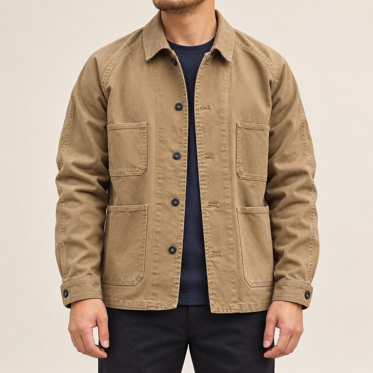 Front view of the khaki four-pocket chore coat worn over a navy shirt