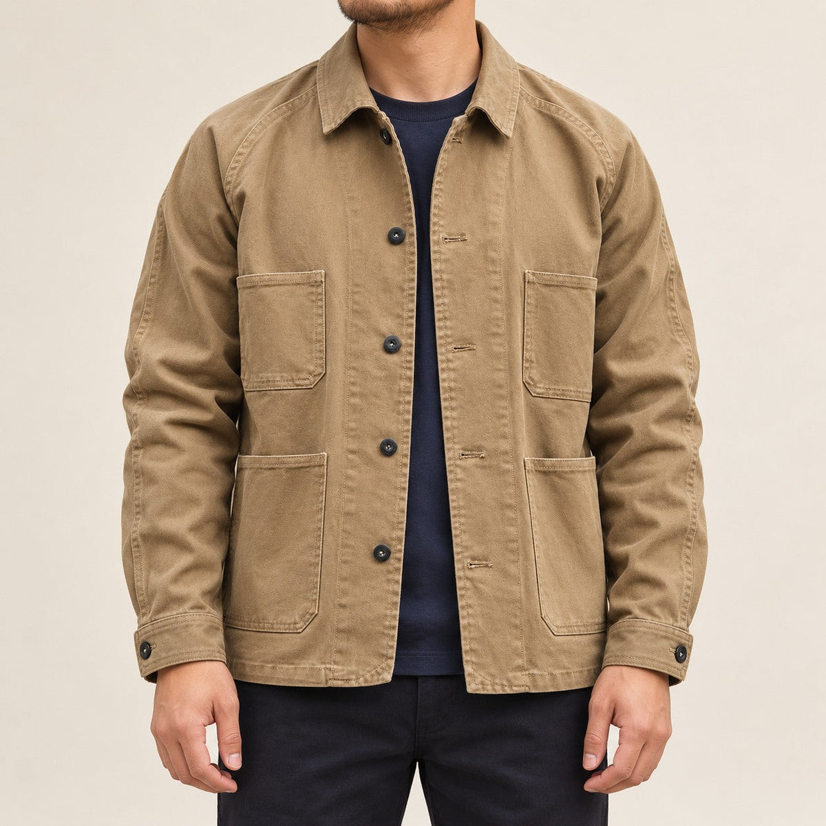 Front view of the khaki four-pocket chore coat worn over a navy shirt