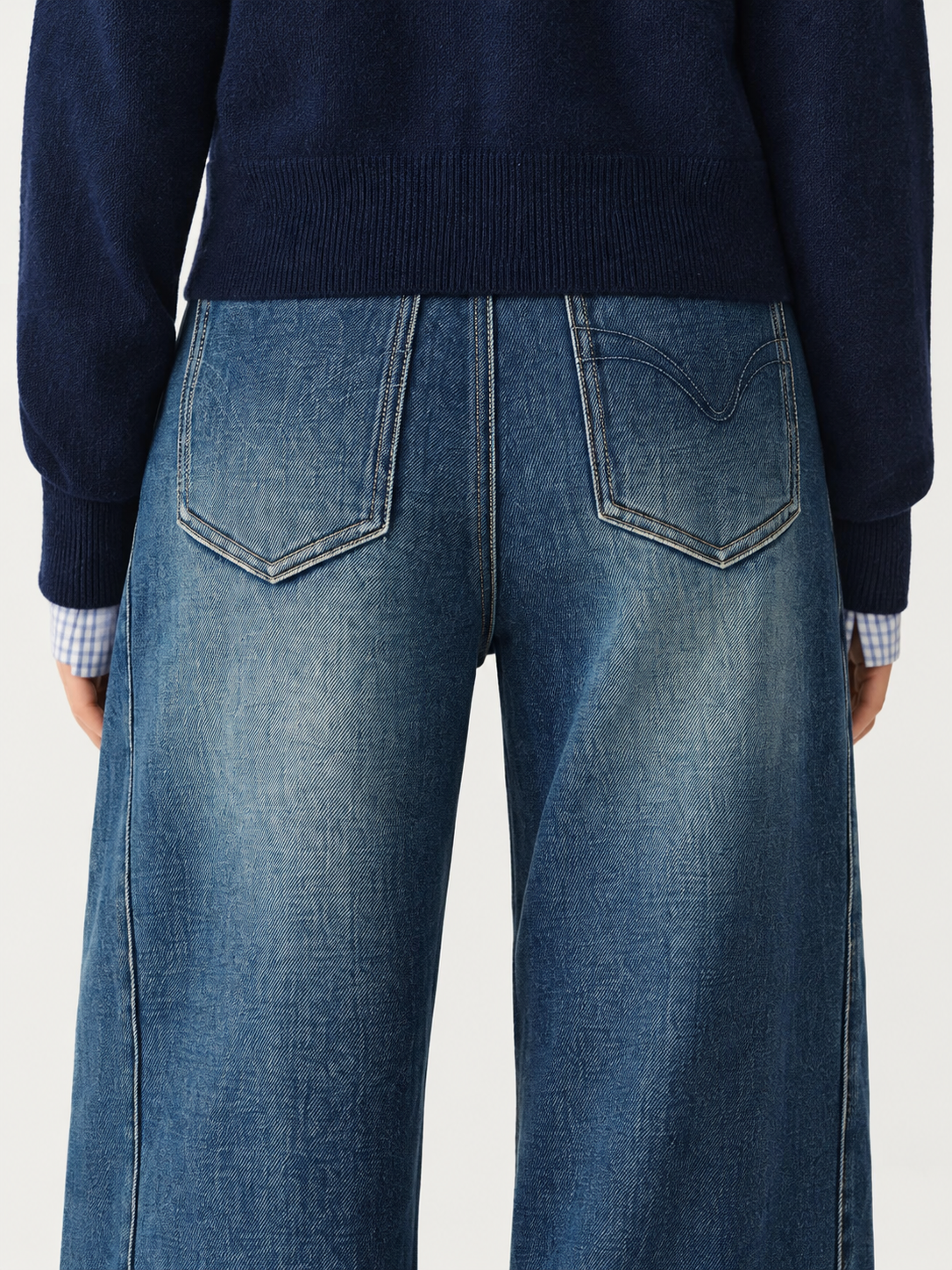 FSLE washed-blue jeans, rear pocket detail with curved stitching on the viewer-right pocket only