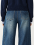 FSLE washed-blue jeans, rear pocket detail with curved stitching on the viewer-right pocket only
