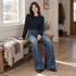 Woman seated on a home entryway bench wearing FSLE washed-blue wide-leg jeans