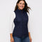 Woman wearing a navy quilted vest over a white long-sleeve shirt on a white background