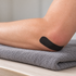 Black SuperSkin strip across an adult elbow resting on a folded towel, illustrating tape appearance and placement