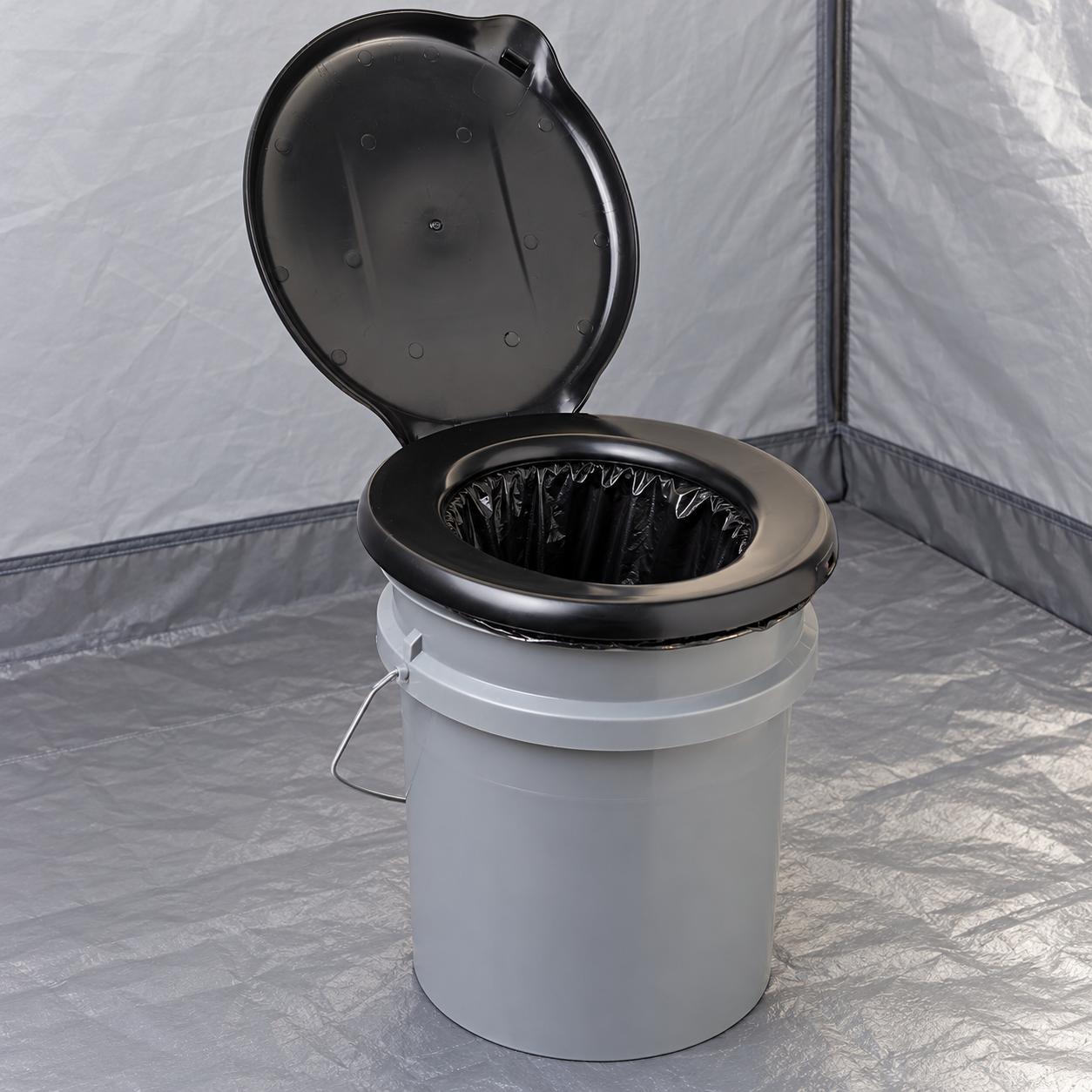 A clean Double Doodie inner bag fitted beneath the seat of a gray Luggable Loo portable toilet, with its empty lined opening visible; toilet sold separately.