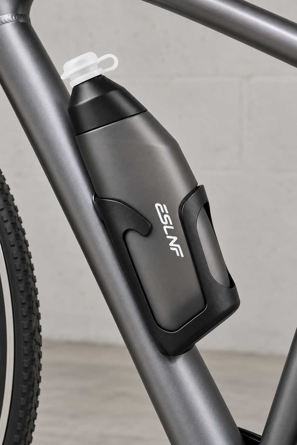 Charcoal contour cycling bottle in its matching black holder mounted inside a bicycle frame; bicycle is illustrative and not included
