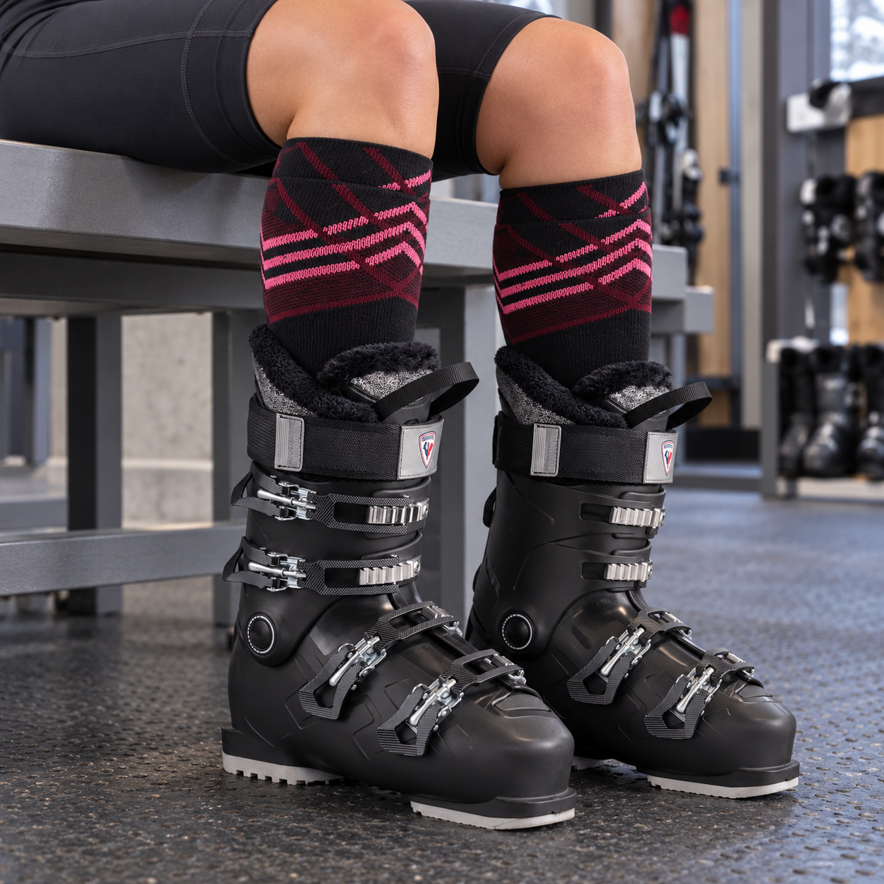 Women's Summit ski sock cuffs visible above black alpine ski boot liners in a resort boot room.