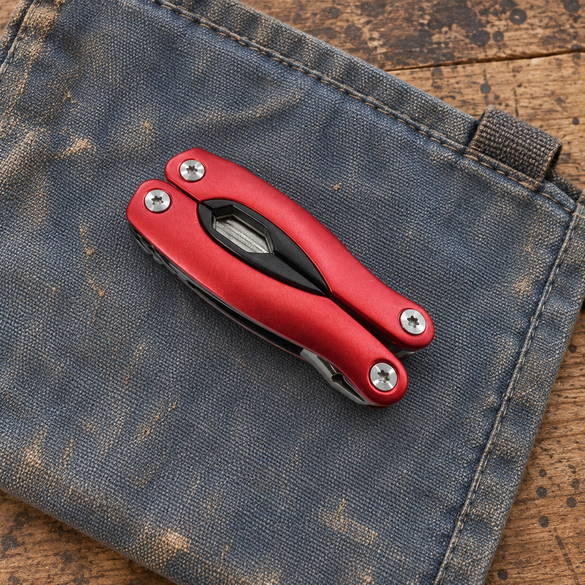 One folded red AceCamp multi tool resting on a canvas work surface