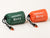 One orange and one green packed bivy cover in drawstring pouches with two orange-and-black whistles