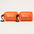 Two orange packed bivy covers in drawstring pouches without whistles