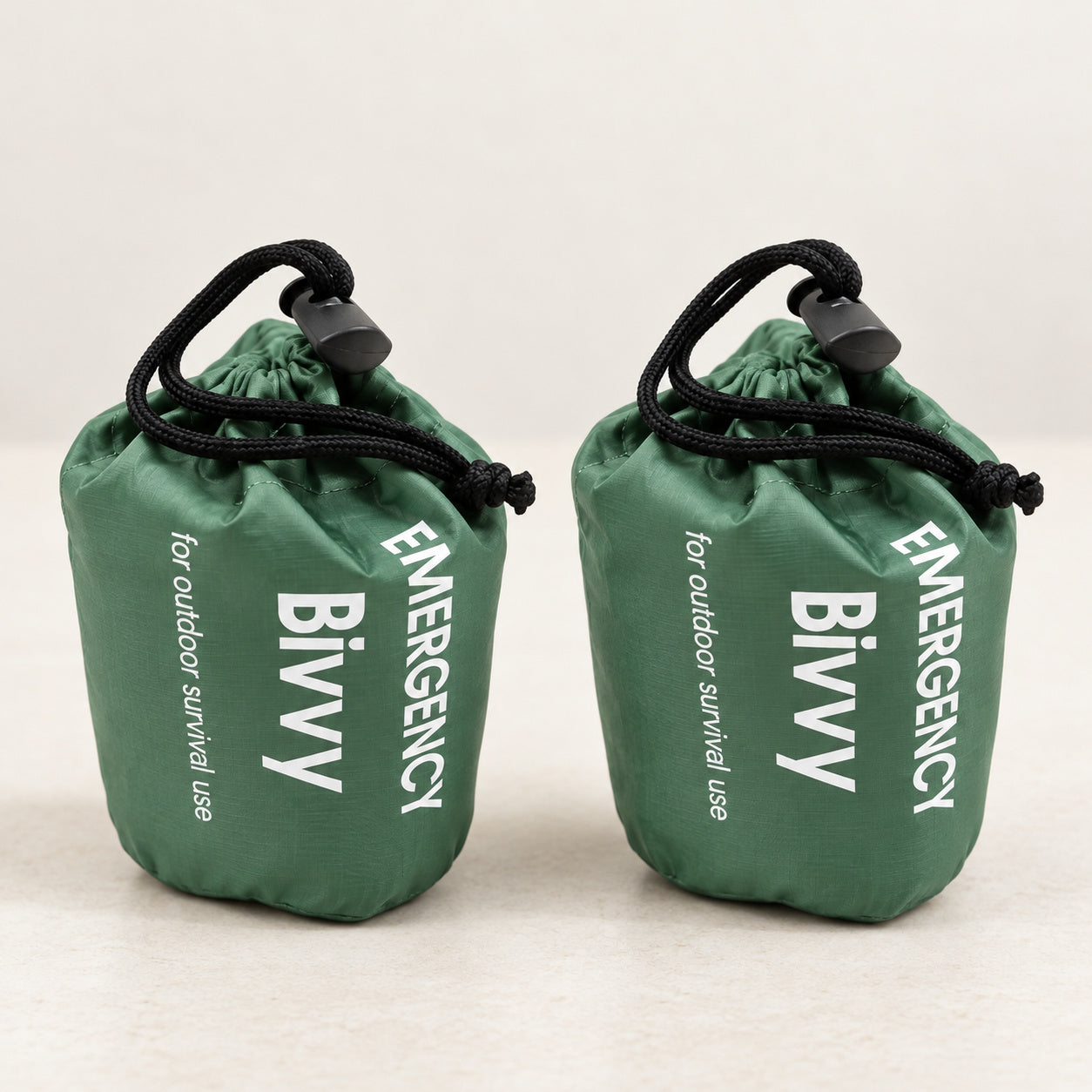 Two green packed bivy covers in drawstring pouches without whistles
