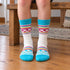 A matching white and turquoise patterned pair from the Bridgedale kids ski sock two-pack, worn at home.