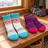 Two matching pairs of White/Purple Bridgedale kids ski socks on a wooden bench.