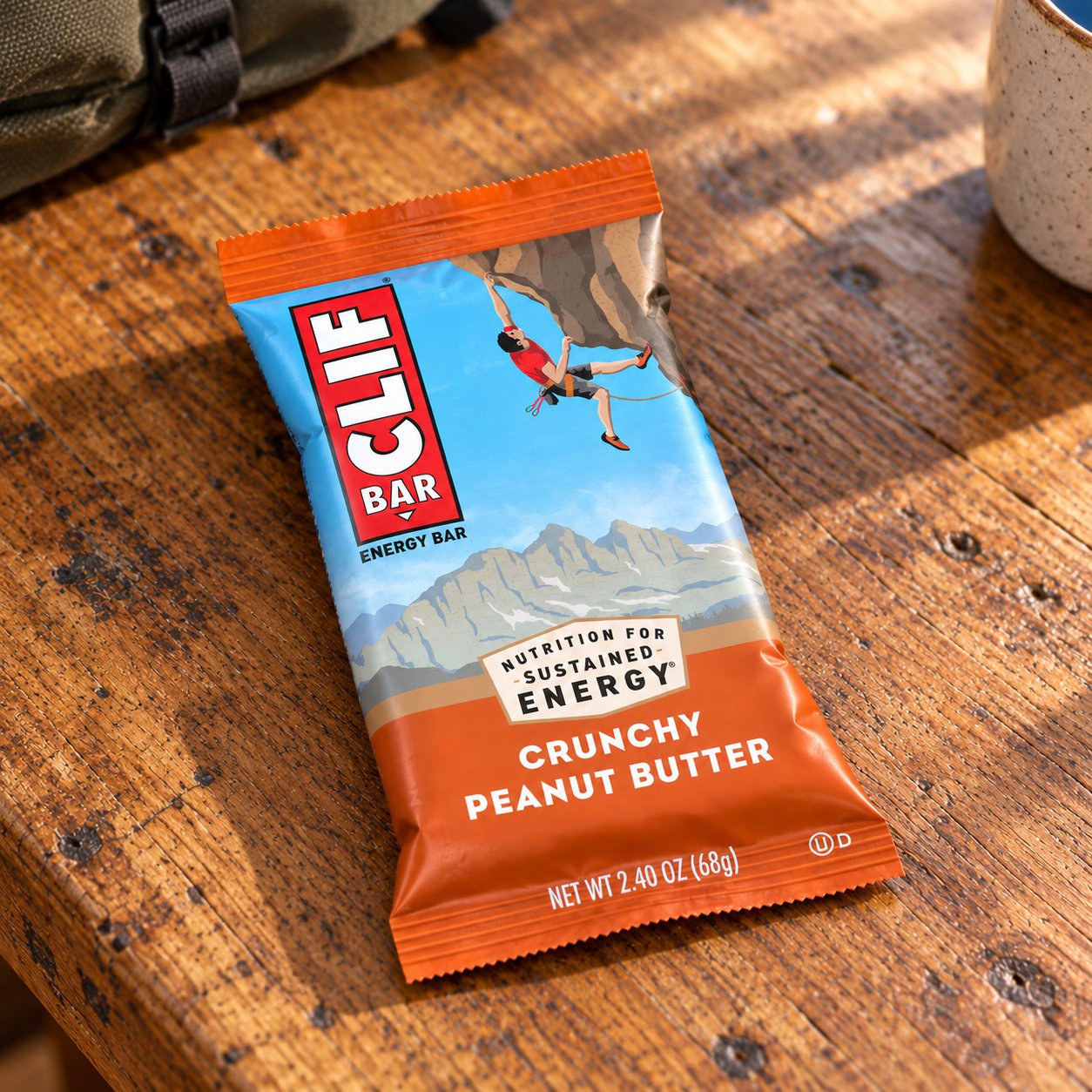 One wrapped Crunchy Peanut Butter CLIF bar lying on a wooden table.