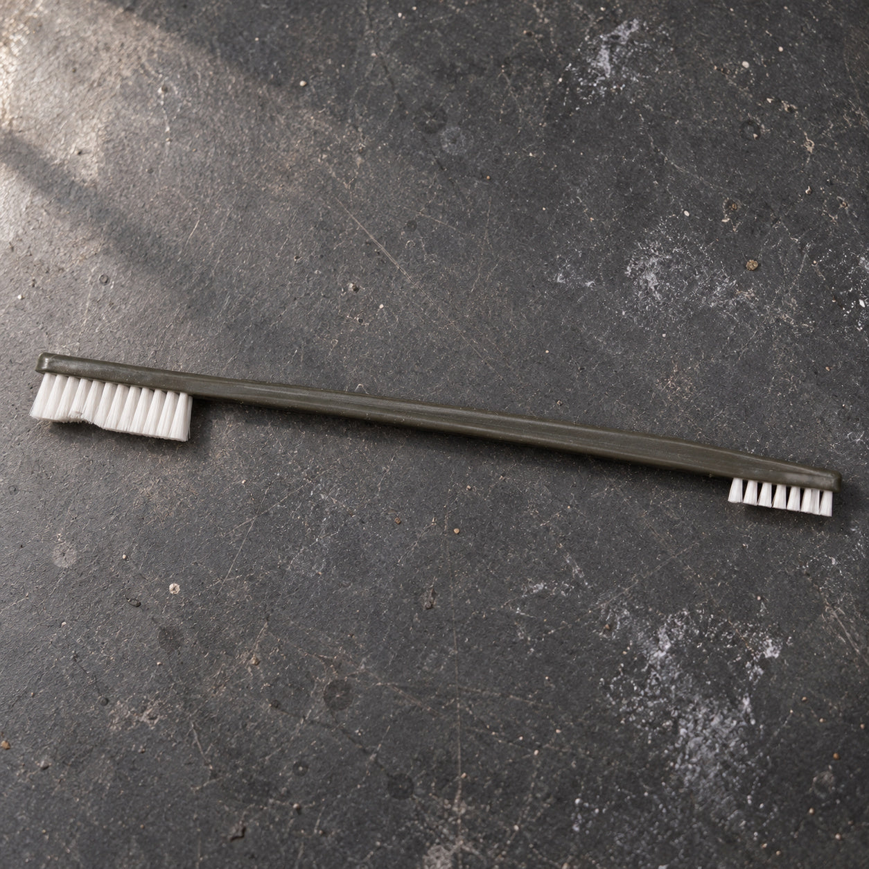 Cypher X Brush laid across a dark maintenance workbench with both heads visible