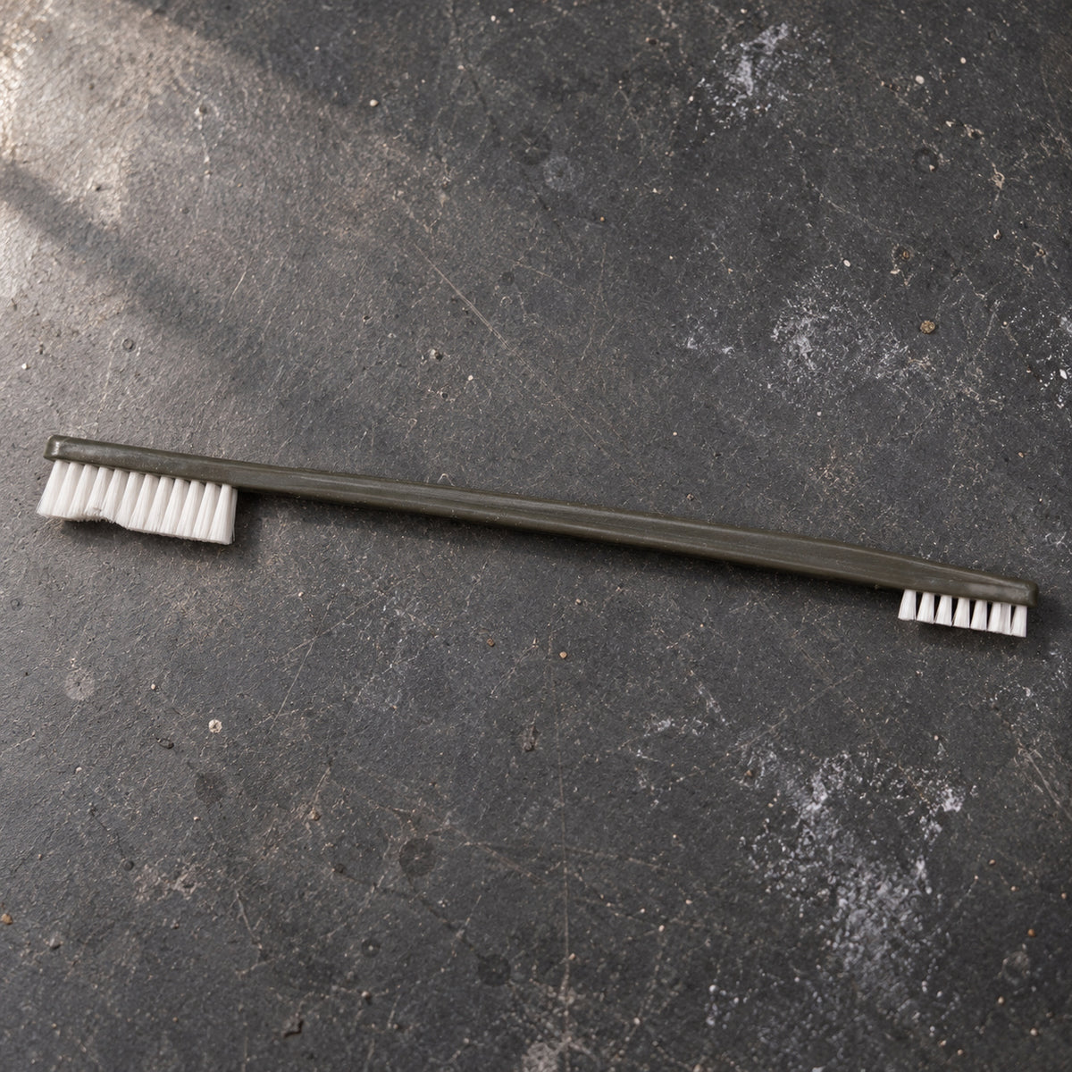 Cypher X Brush laid across a dark maintenance workbench with both heads visible