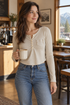 Woman wearing the apricot Maden ribbed cropped Henley with high-waisted jeans in a coffee shop