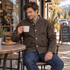 Man seated at a coffee-shop table wearing the brown-toned Maden work jacket