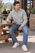 Man in the light gray heather quarter-zip seated at a casual brewery patio table.
