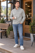Man wearing the light gray heather quarter-zip pullover with jeans on a coffee shop porch.