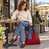 Woman seated outside a coffee shop with the burgundy colorblock shoulder tote and curved stitched front detail