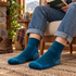 Person relaxing with a book in deep teal blue socks and cuffed jeans.