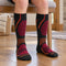 Black Fox River Boreal kids ski socks with orange and magenta details, worn while seated.