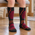Black Fox River Boreal kids ski socks with orange and magenta details, worn while seated.