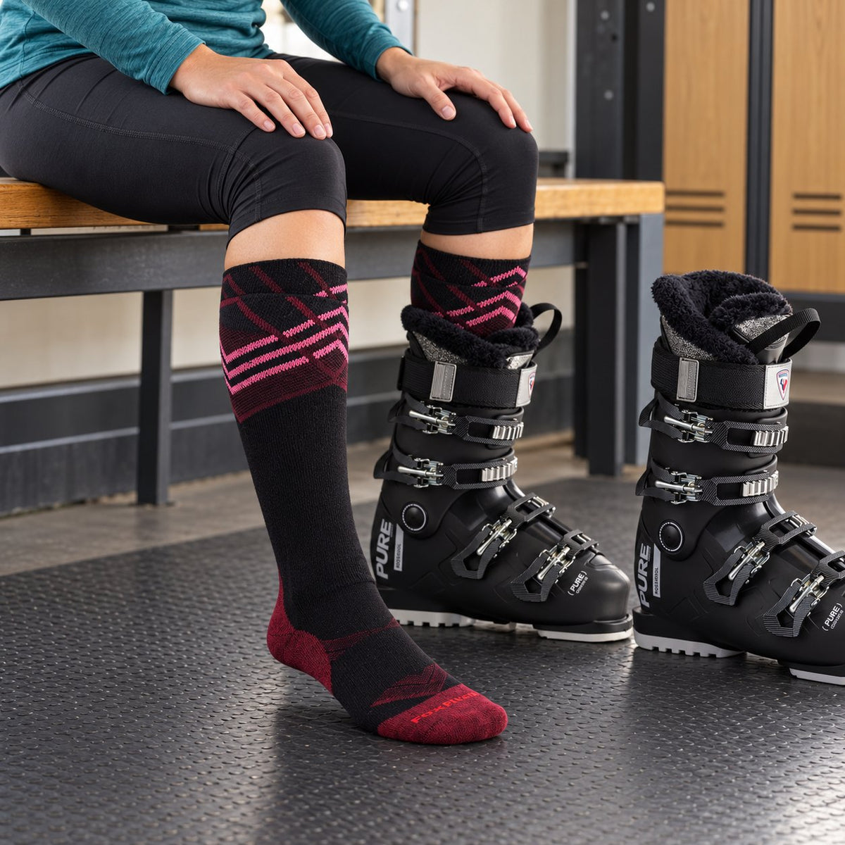 Women's Summit ski socks during ski preparation, with one foot in a black alpine ski boot and the other sock fully visible.