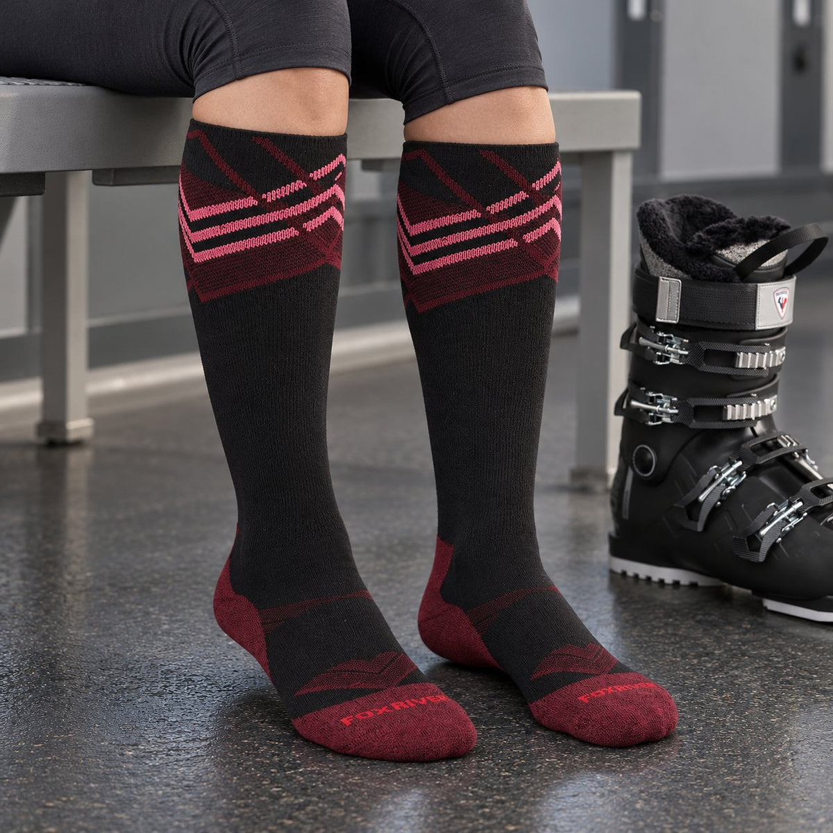 Women's Summit ski socks worn from below the knees to the toes while seated in a ski boot preparation room.