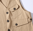Close view of khaki vest flap pockets, dark buttons, and side adjustment tab.