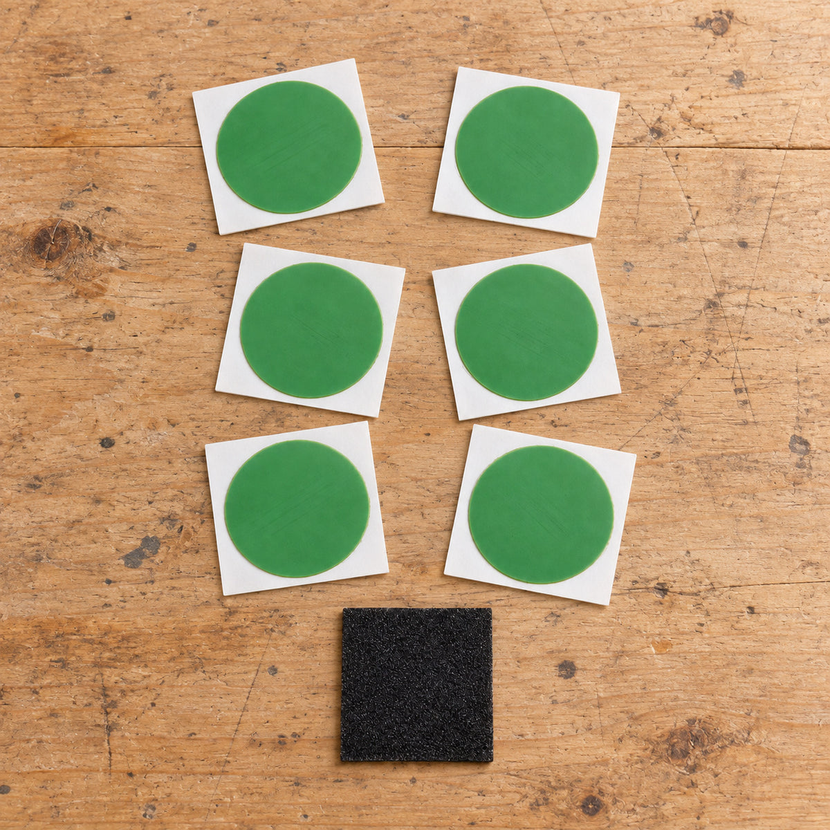 Six Planet Bike patch cards and the abrading square arranged on a wooden repair bench