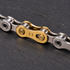 Gold YBN QRs11 11-speed quick link joining a silver bicycle chain on a dark repair mat