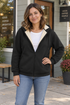 Woman wearing a black fleece-lined zip hoodie outside a neighborhood coffee shop.