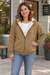 Woman wearing a khaki fleece-lined zip hoodie outside a neighborhood coffee shop.