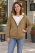Woman wearing a khaki fleece-lined zip hoodie outside a neighborhood coffee shop.