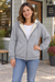 Woman wearing a light gray fleece-lined zip hoodie outside a neighborhood coffee shop.