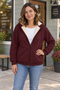 Woman wearing a wine fleece-lined zip hoodie outside a neighborhood coffee shop.
