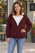 Woman wearing a wine fleece-lined zip hoodie outside a neighborhood coffee shop.