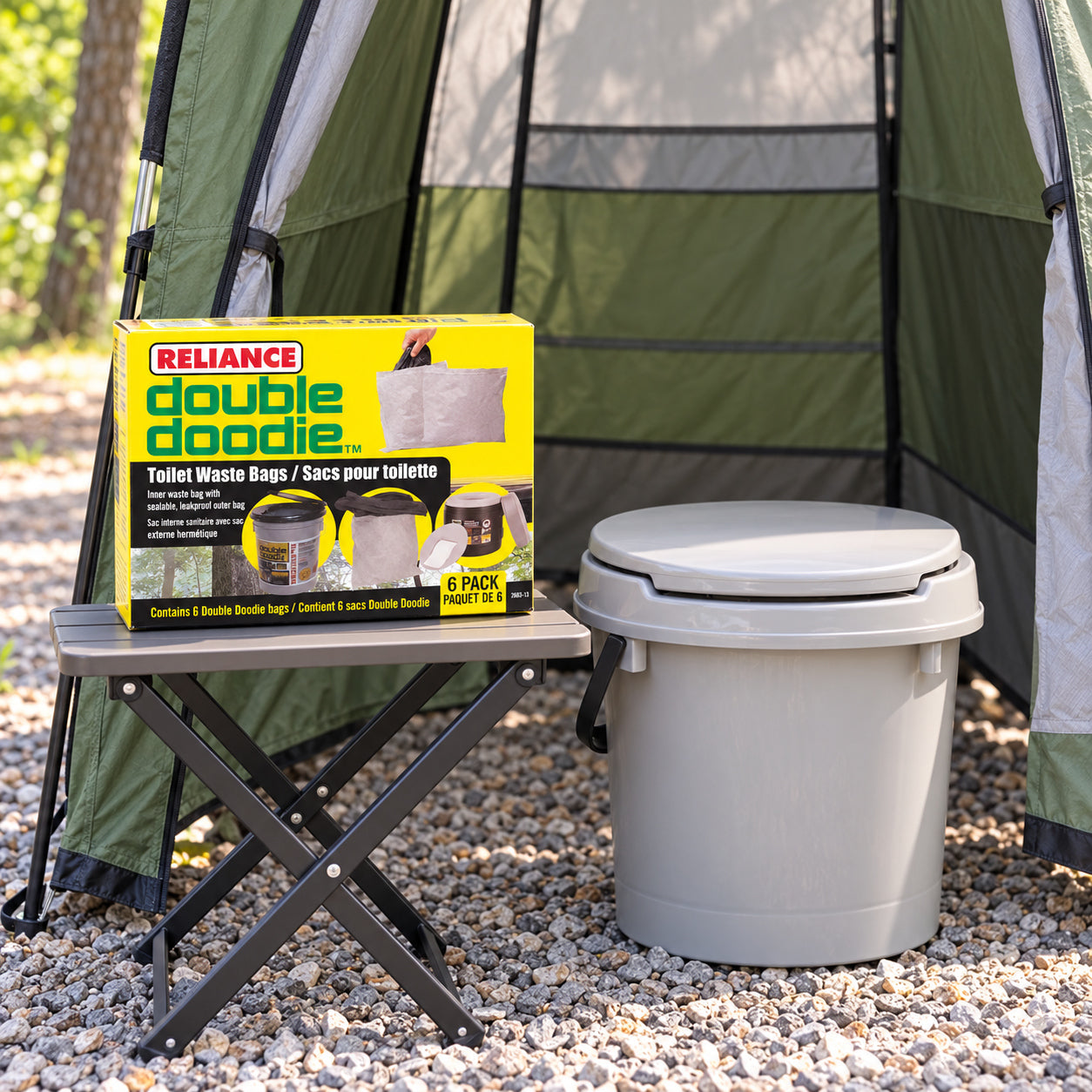 A Reliance Double Doodie gel-free six-pack carton beside a closed portable toilet in a campsite privacy shelter.