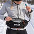 Flow 1.5L reservoir seated in an open SILVA Flex Belt 10, with its insulated hose extending from the belt side to a hand-held blue and gray bite valve; belt and clothing not included.