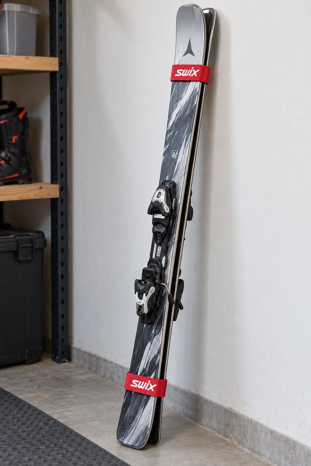 Two red SWIX straps securing a realistic mounted alpine ski pair base-to-base in a gear room.