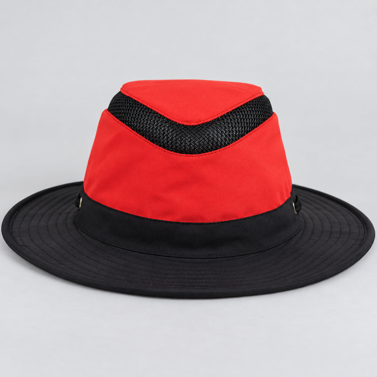 Red and black Tilley LTM6 Airflo hat on a neutral studio surface, showing the crown mesh band and complete brim.