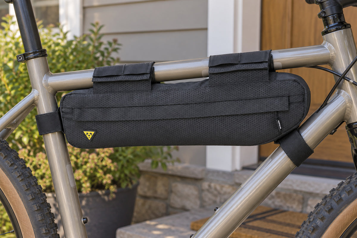 Black Topeak MidLoader 4.5L bag mounted inside a bicycle frame beside a home porch