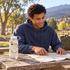 Clear Camo Nalgene bottle on a picnic table beside a map, with a man seated behind it